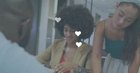 Team collaborating over paperwork at modern office table with heart overlay for engagement