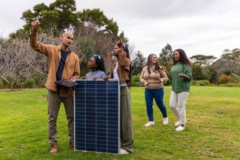 African american group demonstrating solar panel with tablet at outdoor renewable workshop