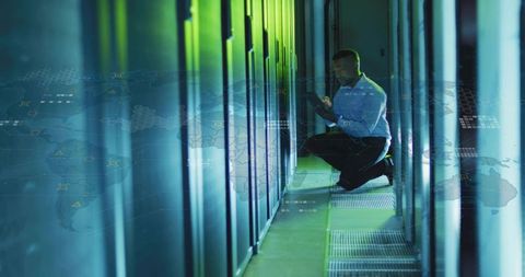 IT Technician Kneeling Inspecting Server Rack with Tablet in Modern Data Center Aisle