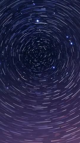 Vertical long-exposure timelapse showing star trails rotating around celestial pole in purple night 