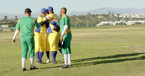 Baseball players embracing on sunlit field celebrating teamwork and postgame camaraderie