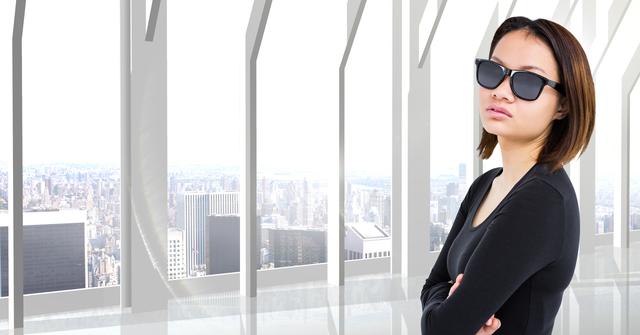 Confident woman wearing sunglasses with arms crossed inside modern building with urban city view. Suitable for business themes, professional settings, urban lifestyle content, fashion and style blogs, and corporate imagery.