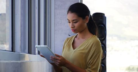 Professional Woman Focused on Tablet near Office Window