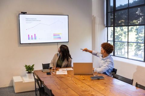 Diverse coworkers presenting digital analytics during collaborative business meeting
