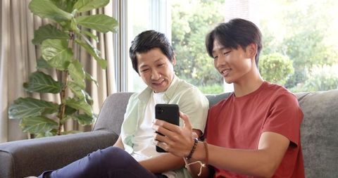 Father and Son Bonding on Sofa with Smartphone