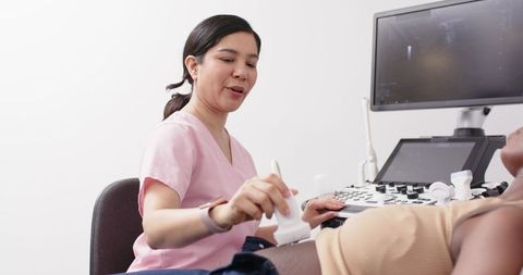 Female sonographer performing abdominal ultrasound on patient using modern ultrasound machine
