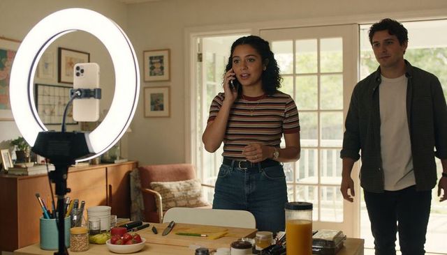 Woman Content Creator Speaking on Phone During Home Cooking Shoot with Ring Light