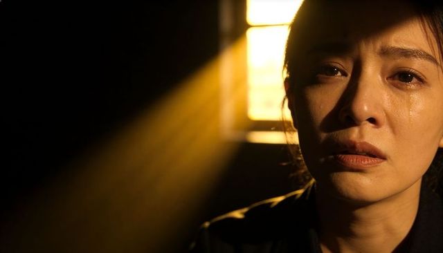 Tearful woman under window light beam, backlit moody portrait for emotional storytelling