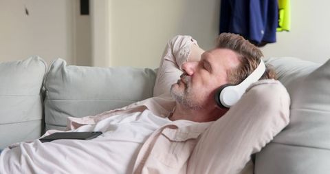 Middle-aged man relaxing with headphones on sofa