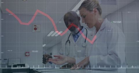 Doctors analyzing data on touchscreen table in modern hospital corridor