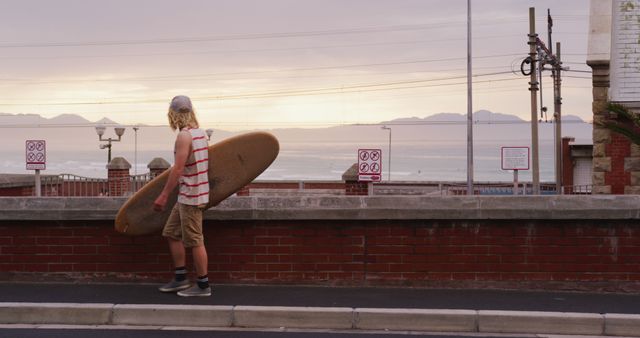 Young Man Carrying Surfboard to Beach at Sunset - Download Free Stock Images Pikwizard.com