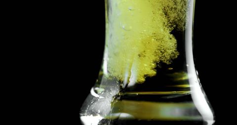 Refreshing Beer Pour with Bubbles and Foam Against Black Background