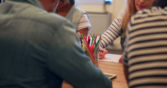 Diverse Group Collaborating at Wooden Table with Colorful Pencils - Download Free Stock Images Pikwizard.com