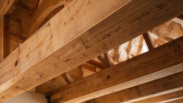 Exposed timber beams creating rustic loft ceiling with metal strap detail