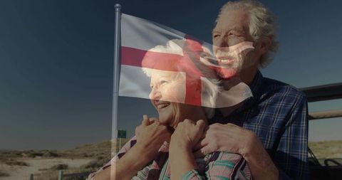 Senior couple embracing by coast with st george flag overlay showing patriotic warmth