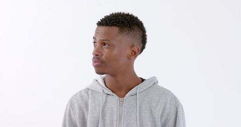 Young Man in Hoodie Reflecting Thoughtfully Against White Background