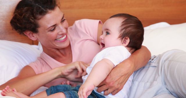 Happy Mother Holding and Playing with Baby on Bed - Download Free Stock Images Pikwizard.com