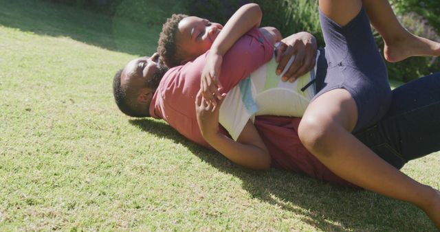 Father and Son Playfully Bonding on Grass in Sunny Park - Download Free Stock Images Pikwizard.com