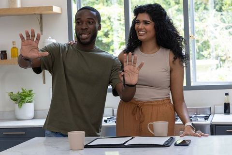 Multicultural couple reviewing home documents at sunny kitchen island