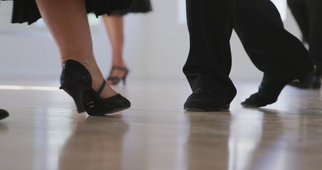 Picture captures feet of couples dancing in ballroom wearing formal shoes. Could be used to highlight elegance and culture of ballroom dancing, promoting dance classes or events, and illustrating articles on dance partnerships and dance techniques.