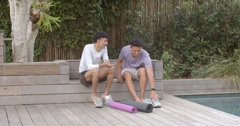 Male Friends Chatting Poolside with Yoga Mats Relaxing Outdoors