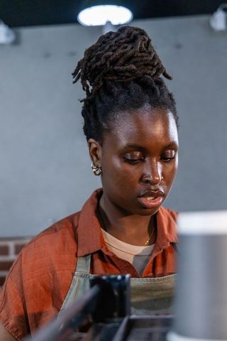 Focused african barista preparing espresso behind commercial machine in urban cafe