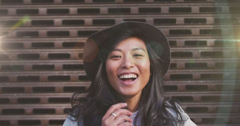Joyful Young Woman Wearing Hat in Urban Setting with Light Flare - Download Free Stock Images Pikwizard.com