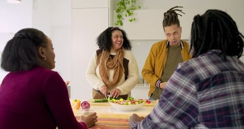 Multicultural friends cooking at kitchen island chopping salad and enjoying conversation