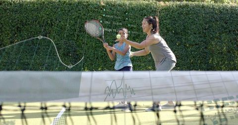 Coach teaching young girl tennis swing on outdoor court with digital analytics overlay