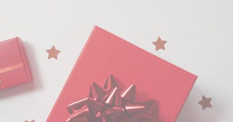 Red gift box with metallic bow and star confetti flatlay for holiday gift marketing