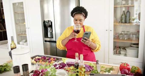 African American Woman Cooking and Using Phone in Modern Kitchen - Download Free Stock Images Pikwizard.com