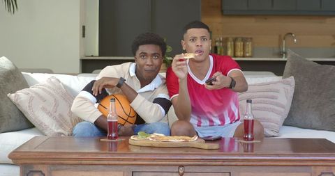 Diverse Male Friends Watching TV Enjoying Pizza at Home