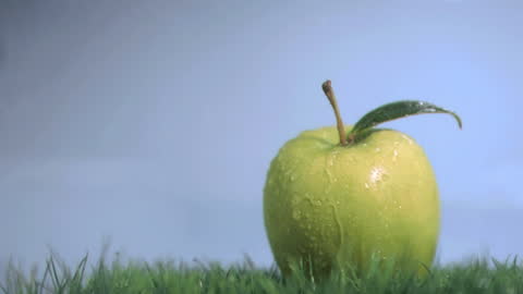 Green Apple with Water Droplets on Grass