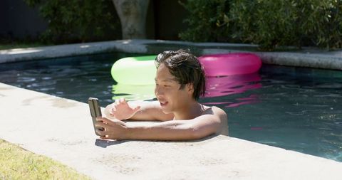 Young Man Relaxing in Pool While Engaged with Smartphone