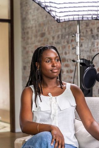 African woman hosting relaxed podcast interview in cozy studio with audio gear
