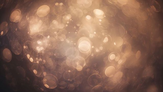 Shimmering golden bokeh orbs with lens flare and warm glow for festive abstract design