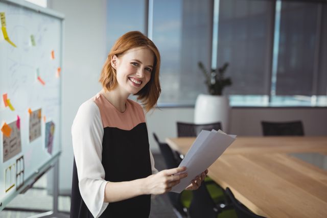 Portrait of smiling executive holding documents in office