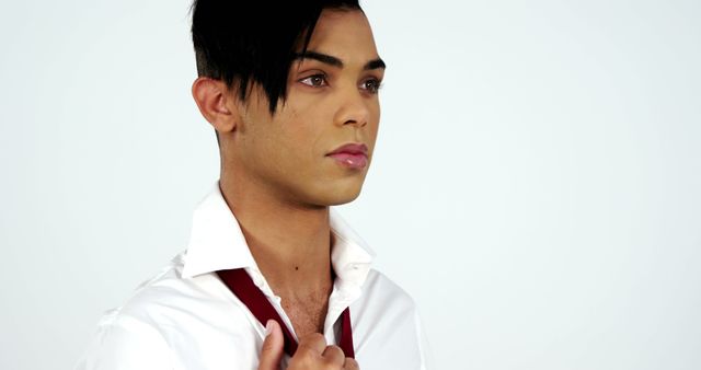 A young Asian man appears in a white shirt, partially unbuttoned, with a contemplative expression, with copy space. His gaze is directed off-camera, suggesting a moment of thoughtfulness or decision-making.