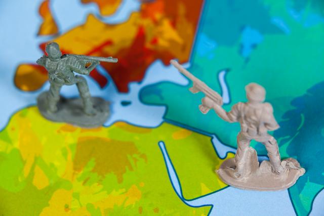 Miniature army soldiers positioned on a colorful map, depicting a battle scene. Ideal for illustrating concepts of military strategy, war games, and combat simulations. Useful for educational materials, game design, and articles on military tactics.