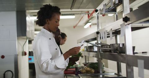 Female Chef Manages Orders in Professional Kitchen Setting