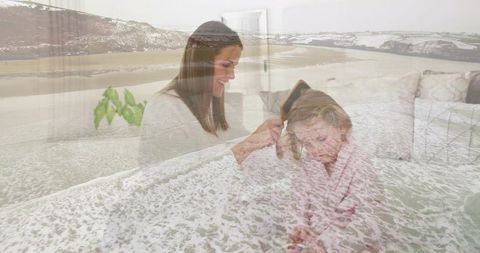 Mother Brushing Daughter Hair on Sofa with Gentle Sea Overlay Feeling Cozy Morning Bonding