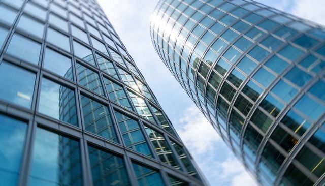 Soaring curved glass towers reflecting blue sky urban skyline modern office facade pattern