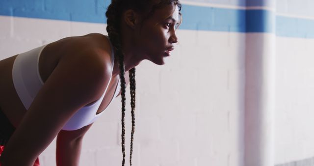 Tired biracial female boxer with braids taking a break training at boxing gym, copy space. Training, boxing, sport, strength and competition, unaltered.