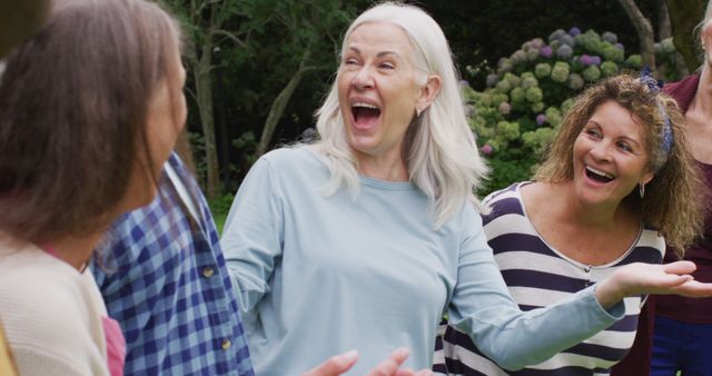 Image of happy diverse female and male senior friends talking and having fun together in garden. retirement lifestyle, spending quality time with friends.
