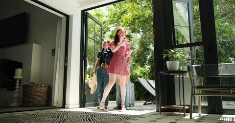 Excited Friends Arriving at Sunny Holiday Home with Luggage