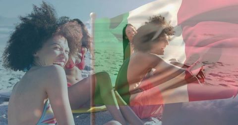 Smiling young women laughing on sunlit beach celebrating summer with italian flag overlay