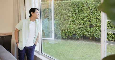 Teenage Boy Gazing Through Sliding Glass Door in Tranquil Home