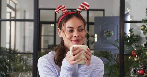 Festive Woman Enjoying Holiday Season Indoors with Hot Beverage