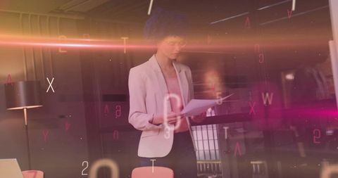 Businesswoman reviewing documents in modern glass office with floating digital letters