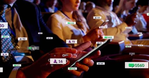 Hands holding smartphone with floating social engagement overlays at business conference